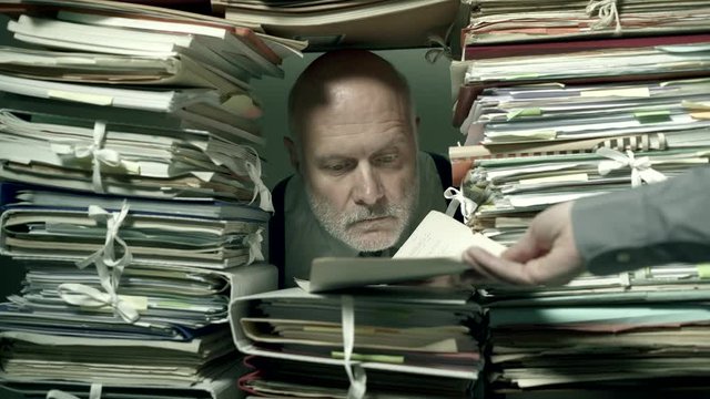 Office clerk working behind a wall of paperwork