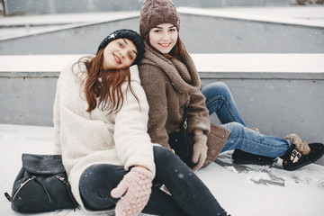 Obraz premium two bright and merry girls sitting in the frozen snowy park