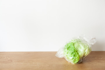 iceberg lettuce vegetable in plastic bag. single use plastic packaging issue