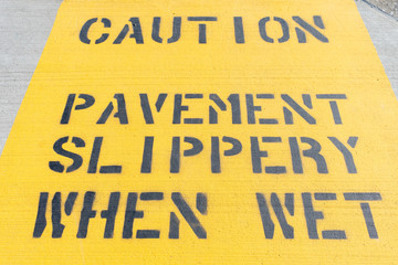 Yellow Caution Pavement Slippery When Wet Sign on the Ground