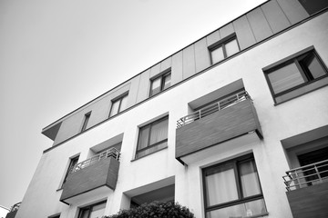  Fragment of a facade of a building with windows and balconies. Modern home with many flats. Black and white.