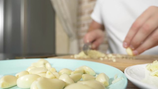 male hands cut garlic on a wooden board. close-up