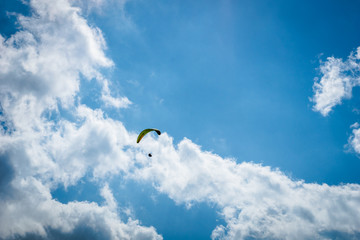 paraglider paragliding over blue sky with white clouds in summer