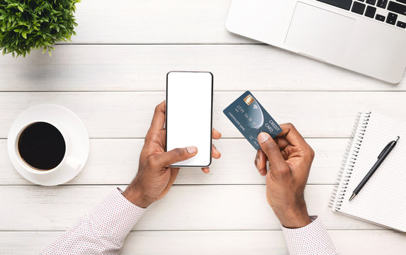 Black man holding smartphone with blank screen and credit card