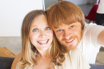 Excited couple having fun at home. Cheerful happy man and woman taking selfie. Home self portrait concept