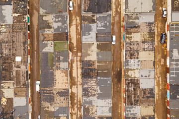 Background pattern consisting of stripes, squares and rectangles of light gray and brown colors: roofs, roads and several cars. The view from the top.