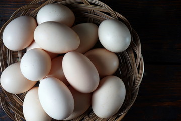 Chicken eggs in a small basket on a dark background.  Natural products, healthy food.