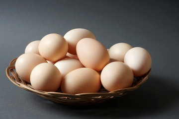 Chicken eggs in a small basket on a dark background.  Natural products, healthy food.