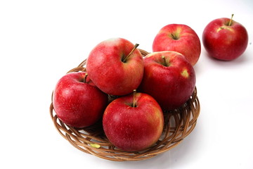 Red ripe apples in a small basket isolated on a white background