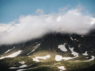 Clouds covering mountain with snow patches