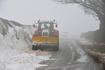 SnowPlow attatchd to tractor clearing snow drifts from country roads in rural Shropshire.