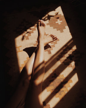 Woman's legs on carpet in sunlight