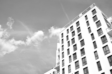 Fototapeta premium Fragment of a facade of a building with windows and balconies. Modern home with many flats. Black and white.