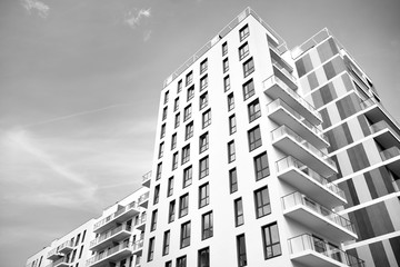 Fragment of a facade of a building with windows and balconies. Modern home with many flats. Black and white.