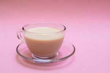 Indian milk tea (masala chai) in a glass cup on soft pink background