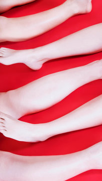 Legs of three people on red surface