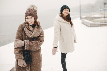 two bright and merry girls walking in the frozen snowy park