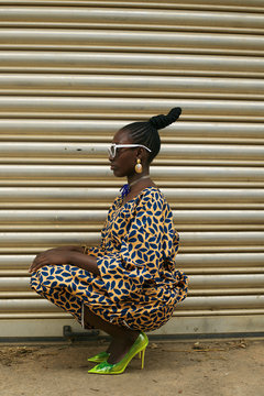 Side view of woman crouching against shutter