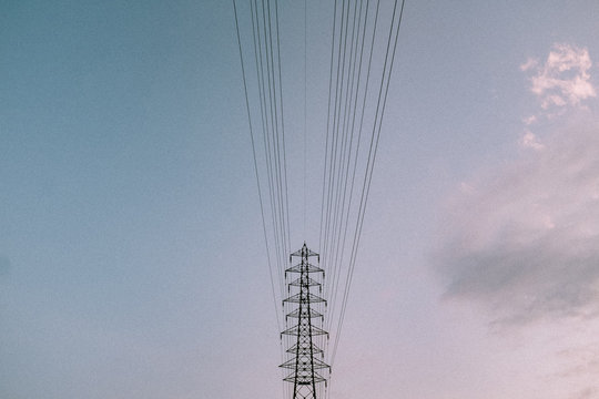 Low angle view of electricity grid against cloudy sky
