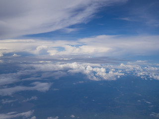 Fototapeta na wymiar Clouds from airplane window with blue sky and high angle ground