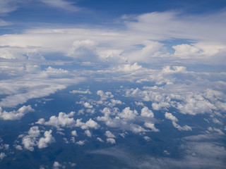 Clouds from airplane window with blue sky and high angle ground