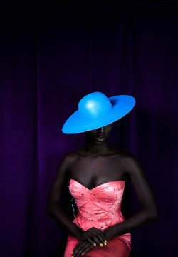 Model wearing blue sun hat and bright pink formal dress