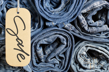 Denim. Lots of blue jeans rolled up. Sale - handwritten inscription on a paper label.