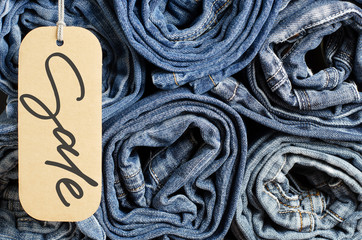 Denim. Lots of blue jeans rolled up. Sale - handwritten inscription on a paper label.