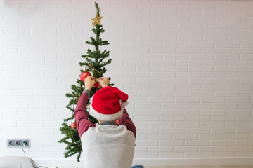 Fototapeta premium boy with his back at home decorating the christmas tree