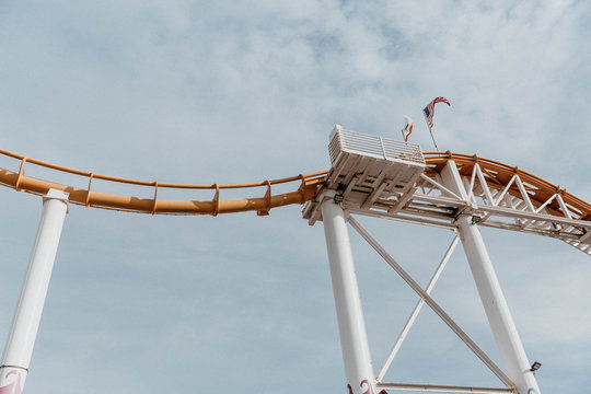 Low angle view of yellow roller coaster tracks against cloudy sky in california at an amusement park