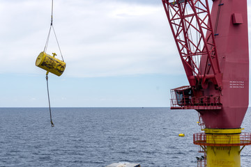 A crane of a construction barge lifting an anchor bouy at oil field