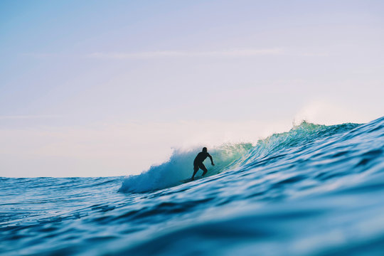 Back-lit surfer rides on wave