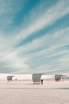 Empty strandkorb beach chairs on beach against cloudy sky