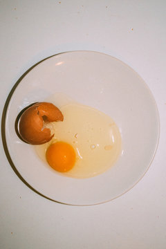 Overhead view of broken egg on plate