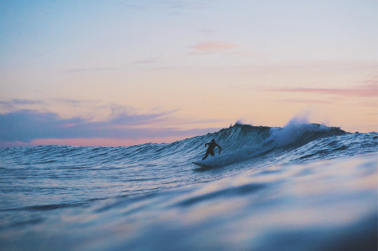 Surfer on wave at sunset