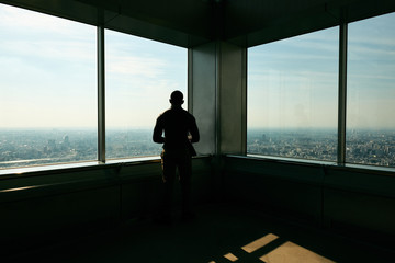 Rear view of man looking at city through window