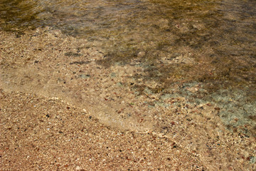 Summer background of hot sand with sea or ocean wave bubbles with copy space for card or advertisement at dawn or sunset