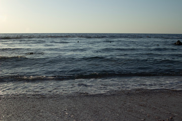 Summer background of hot sand with sea or ocean wave bubbles with copy space for card or advertisement at dawn or sunset
