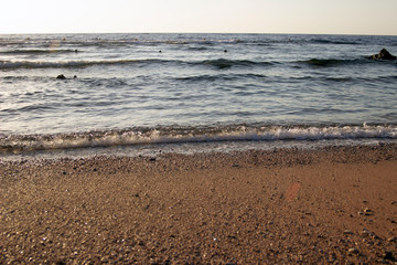 Summer background of hot sand with sea or ocean wave bubbles with copy space for card or advertisement at dawn or sunset