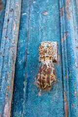 Fragment of an old blue door and a metal arm