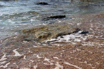 Summer background of hot sand with sea or ocean wave bubbles with copy space for card or advertisement at dawn or sunset