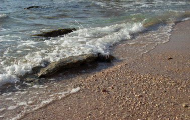 Summer background of hot sand with sea or ocean wave bubbles with copy space for card or advertisement at dawn or sunset