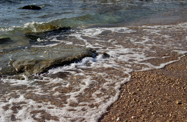 Summer background of hot sand with sea or ocean wave bubbles with copy space for card or advertisement at dawn or sunset