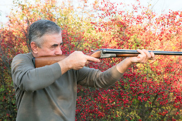 male with double barreled shotgun is taking aim
