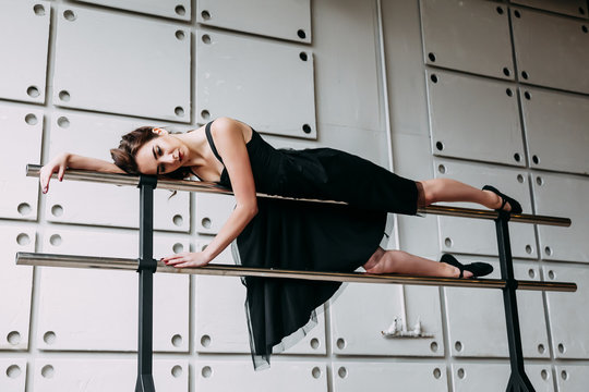 beautiful girl dancer. tired girl dancer. girl ballerina or dancer in a black dress lying on a ballet barre in a dance Studio.