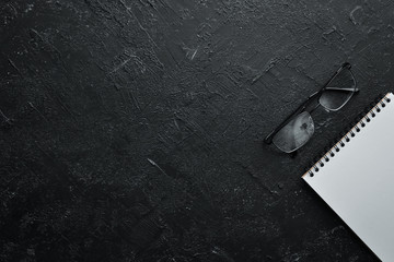 Reading glasses on black stone background. Top view. Free copy space.