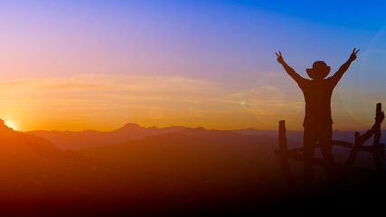 silhouette picture backpacker man show two finger victory sign with lens flare sunset and mountain...