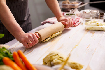 Rolling the dough for dumplings. The housewife rolls the dough with a rolling pin.