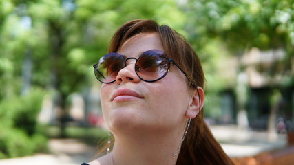 Awesome young woman looking up with cool reflection in her sunglasses