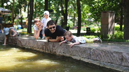 Happy family, little boys with his parents at the parapet of fountain